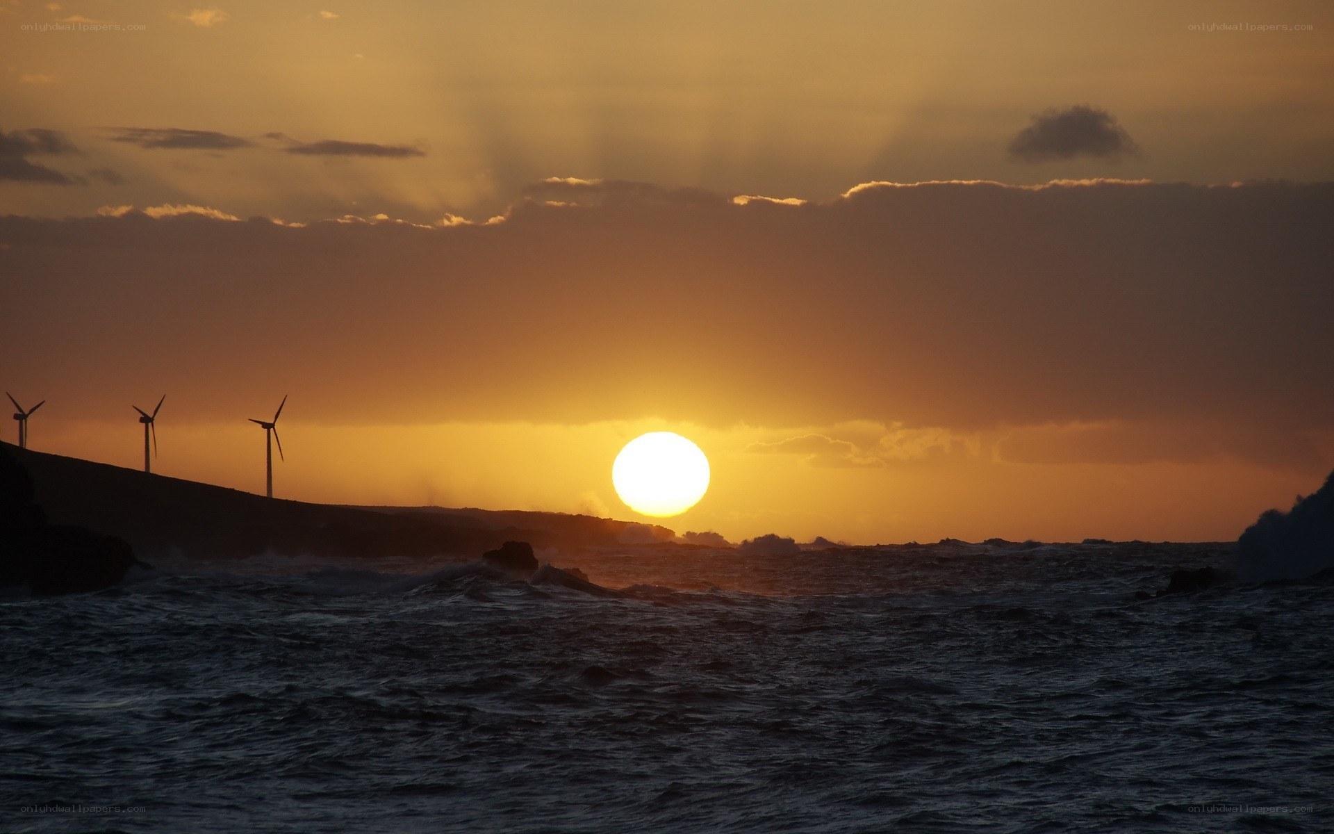 Sunset over ocean with wind turbines