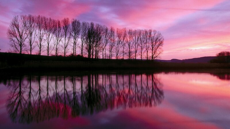 sunset over river with tree reflections