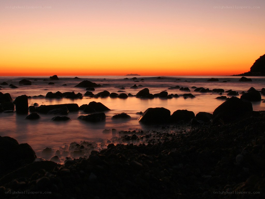 sunset over rocky beach