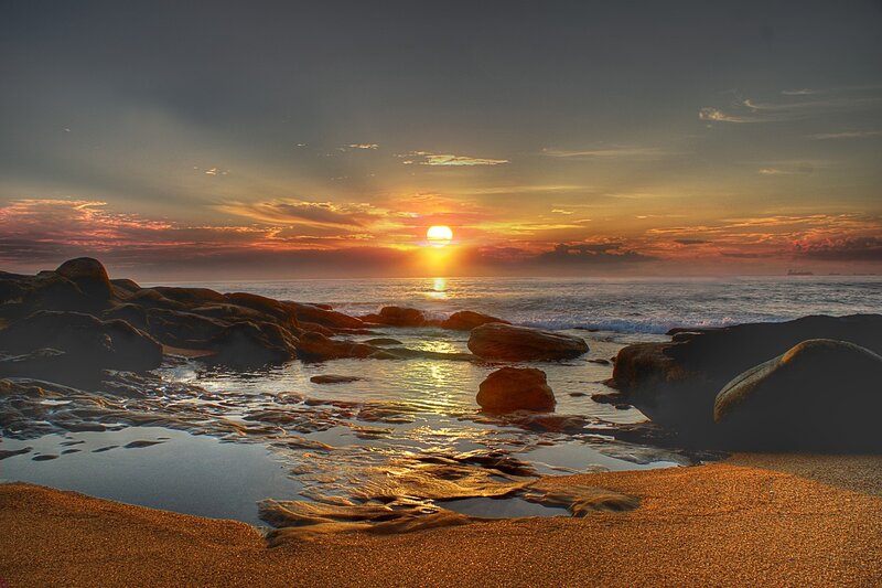 Sunset over Rocky Beach — Orange, Serene, Photograph, Sun, Ocean, Rocks, Sand, Blue