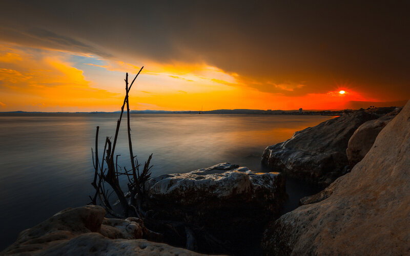 Sunset over Rocky Shore — Orange, Dramatic, Photograph, Rocks, Driftwood