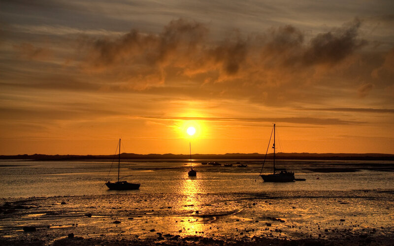 Sunset over sailboats at low tide