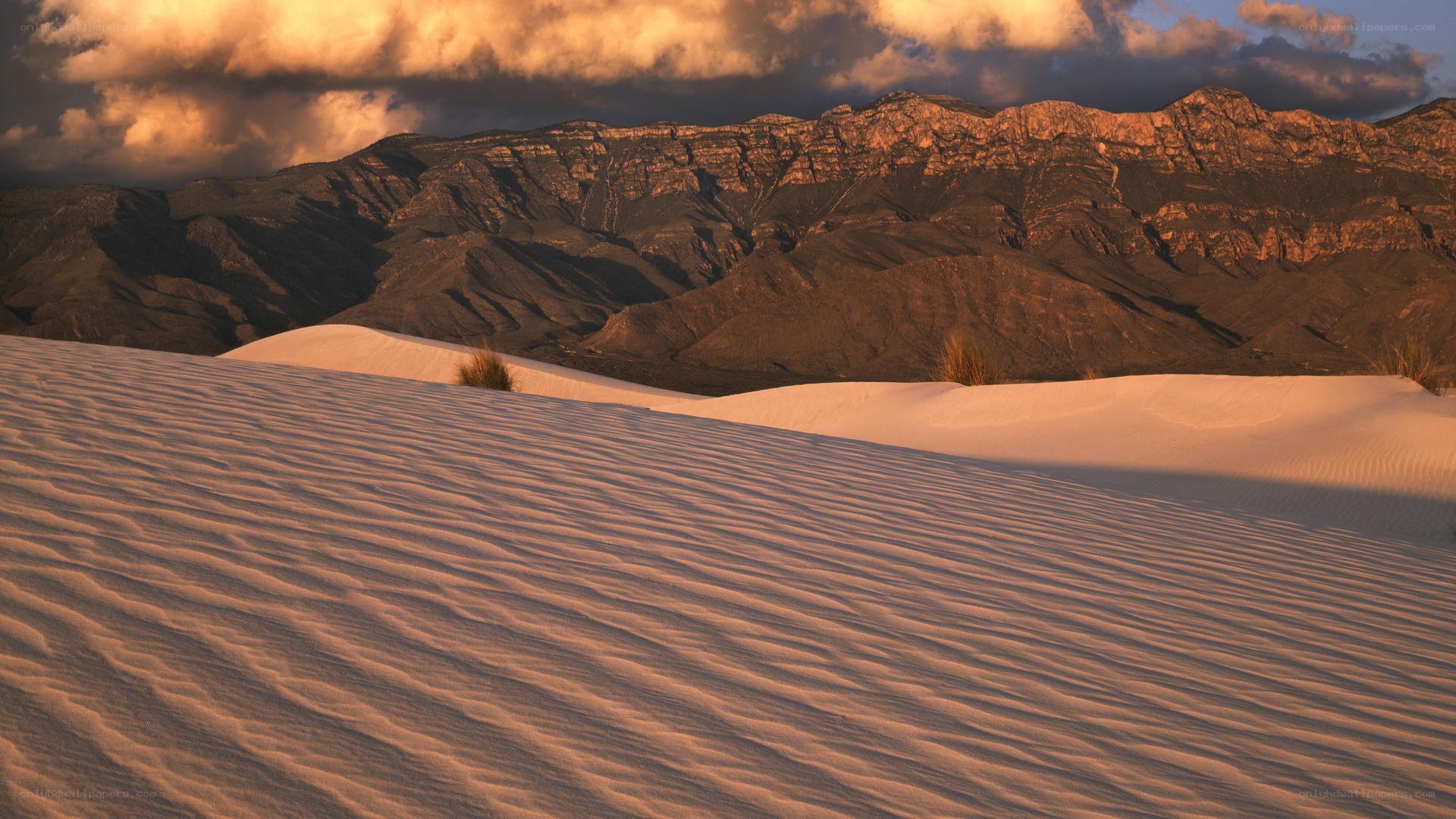 sunset over sand dunes and mountains