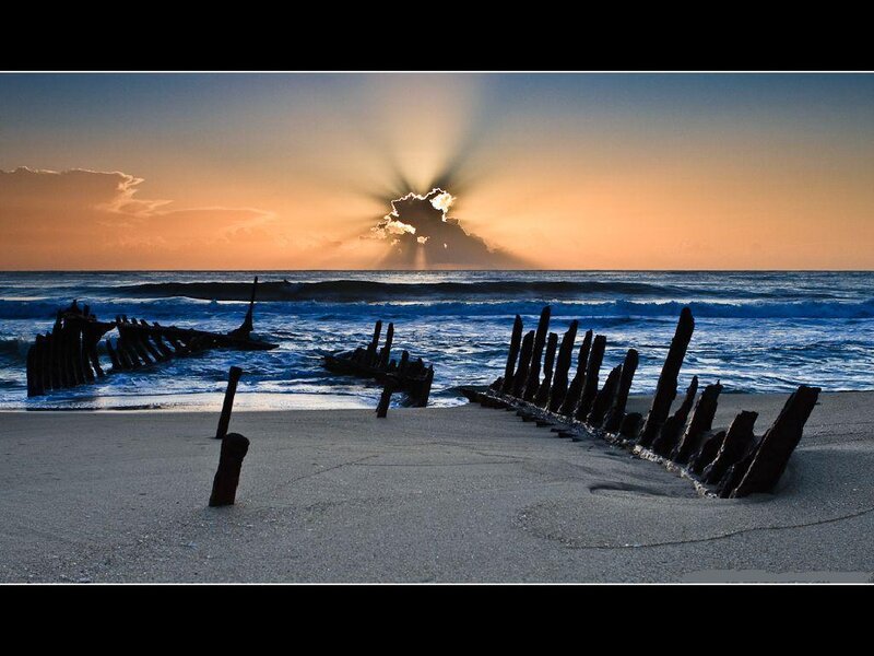 Sunset over shipwreck on beach