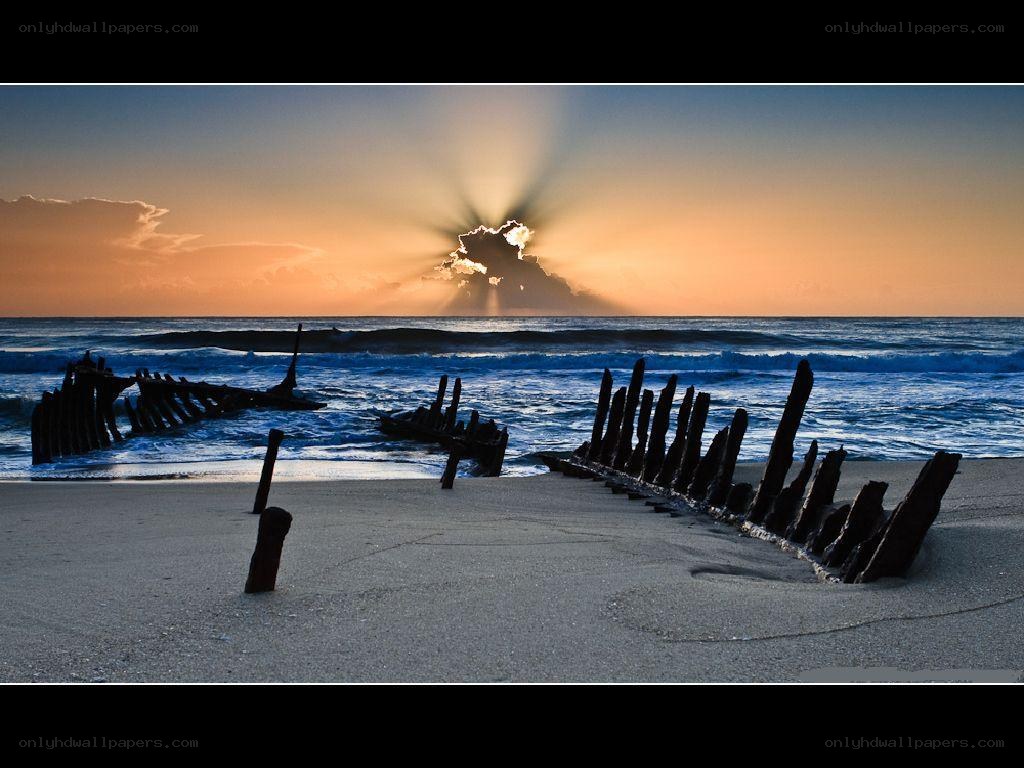 Sunset over shipwreck on beach