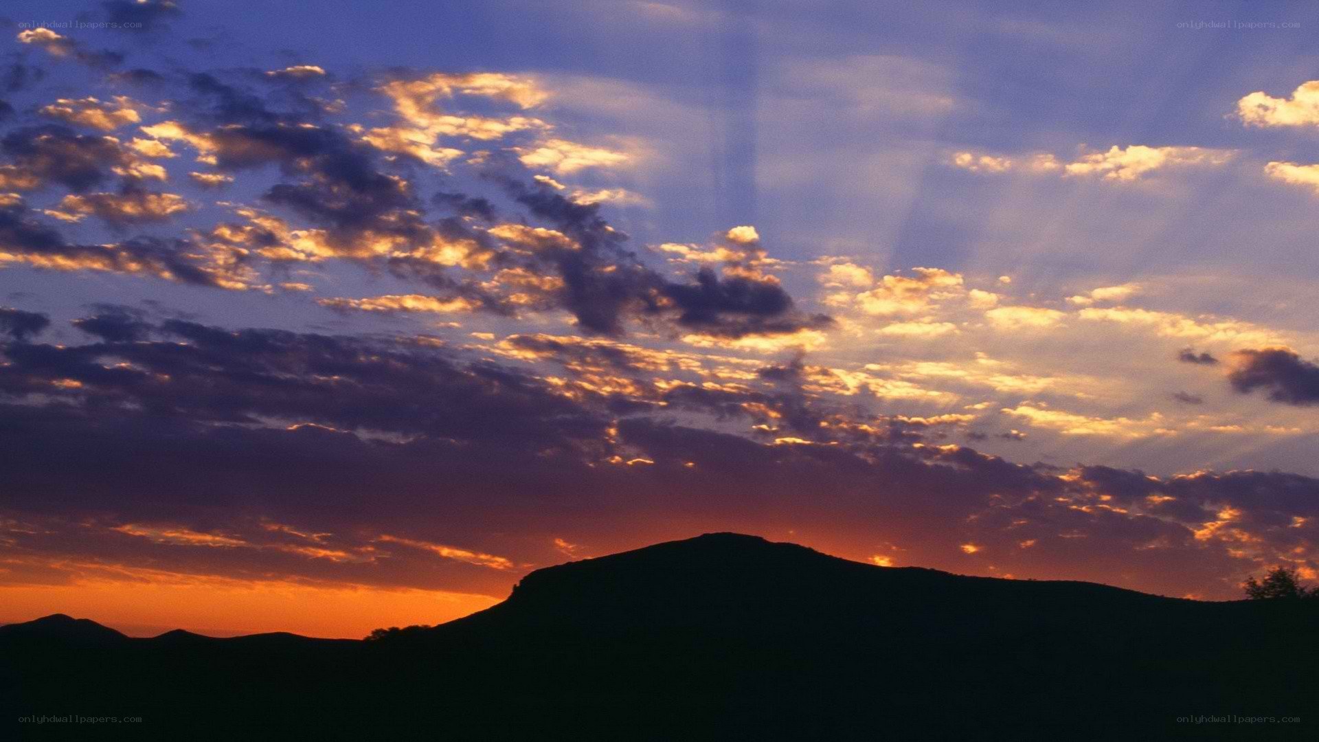 sunset over silhouetted hills