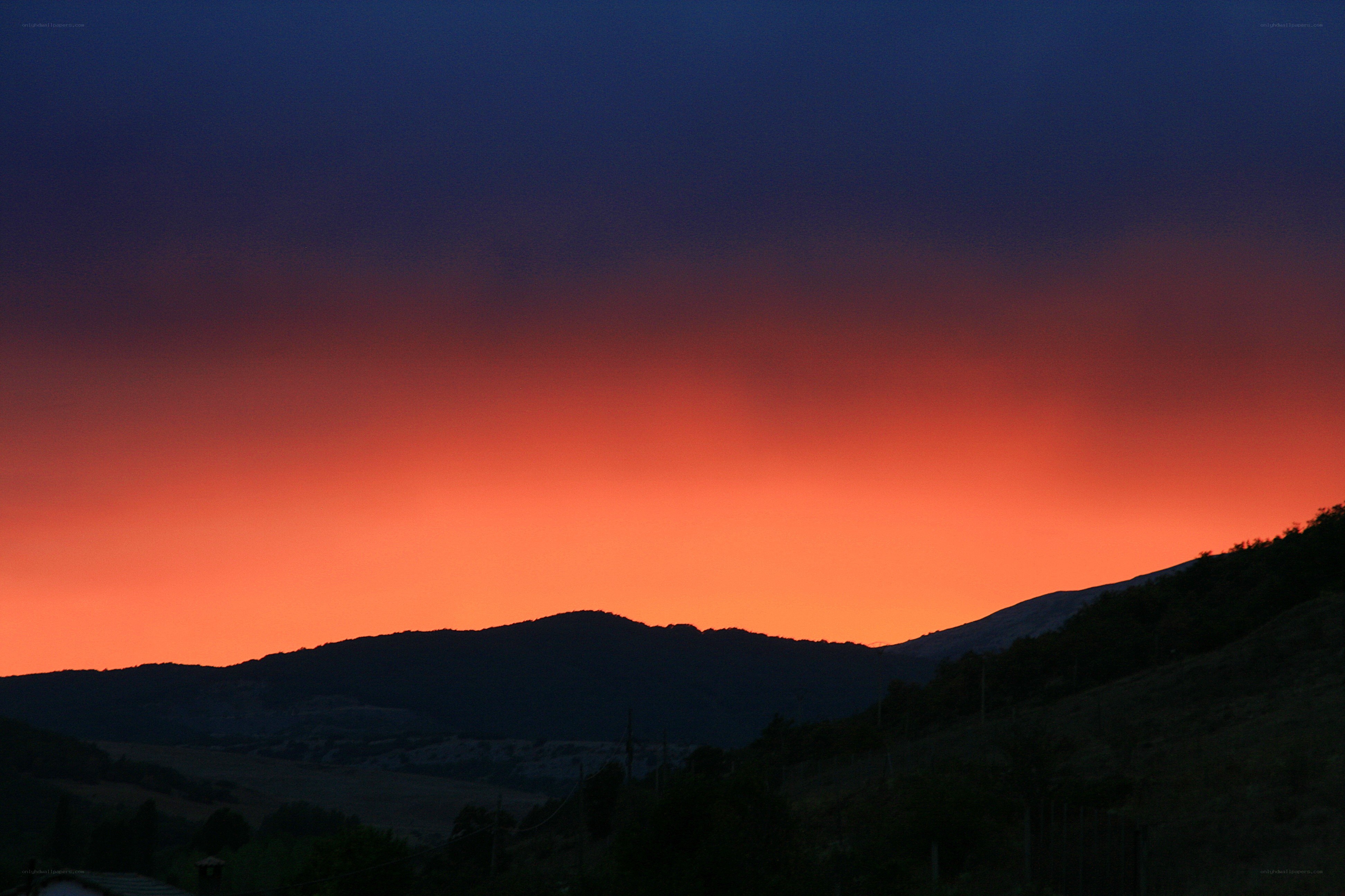 sunset over silhouetted hills