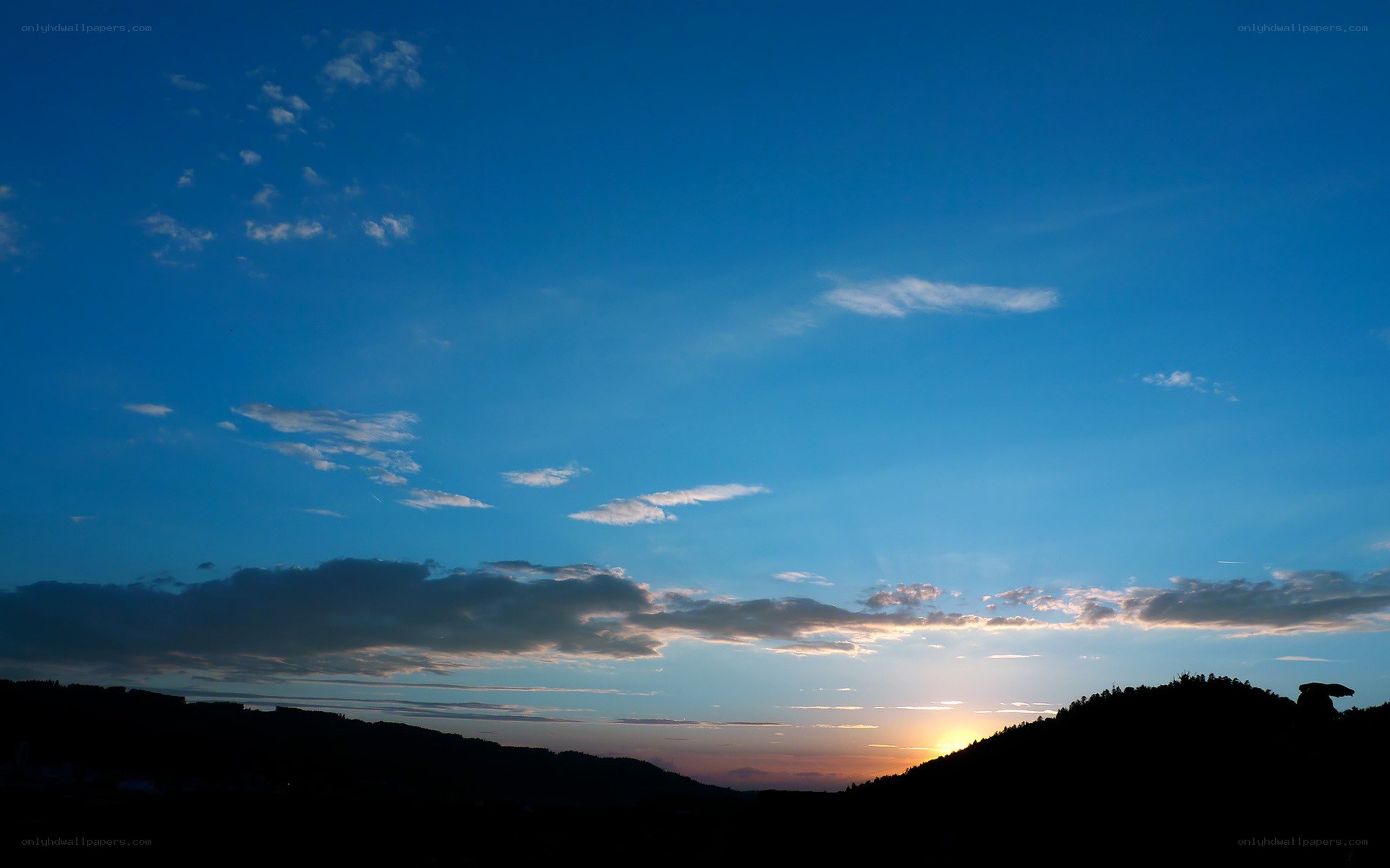 sunset over silhouetted hills