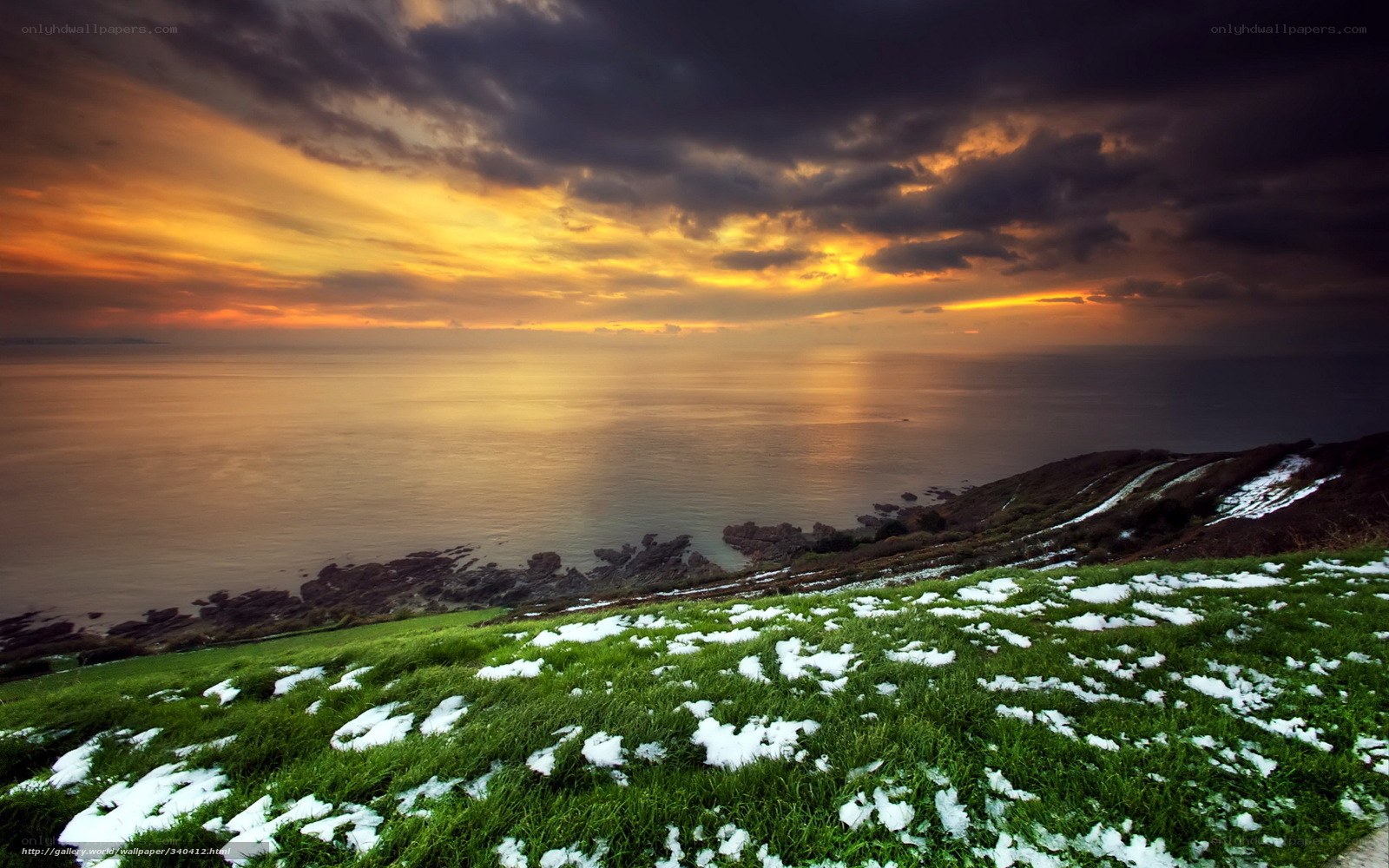 Sunset over snowy coastal hills