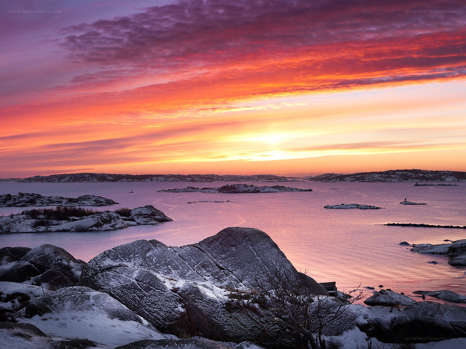 Sunset over snowy coastal rocks