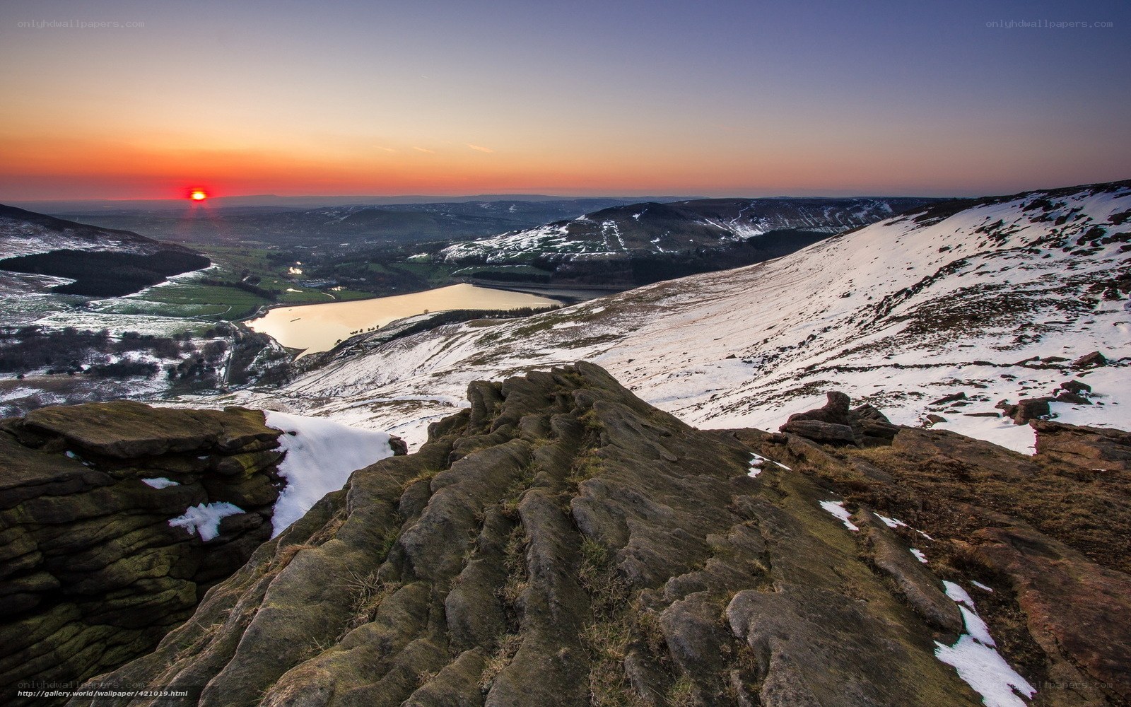 Sunset over snowy hills and lake