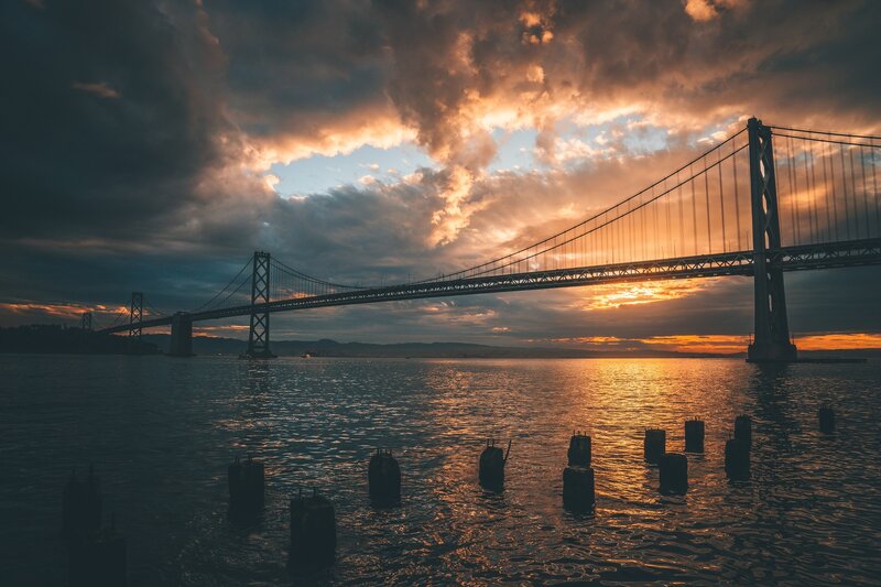 Sunset over Suspension Bridge — Orange, Dramatic, Photograph, Water, Clouds