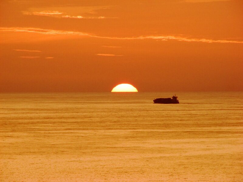 Sunset over the ocean with a ship