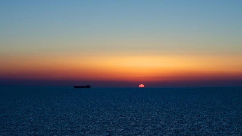 Sunset over the ocean with a ship