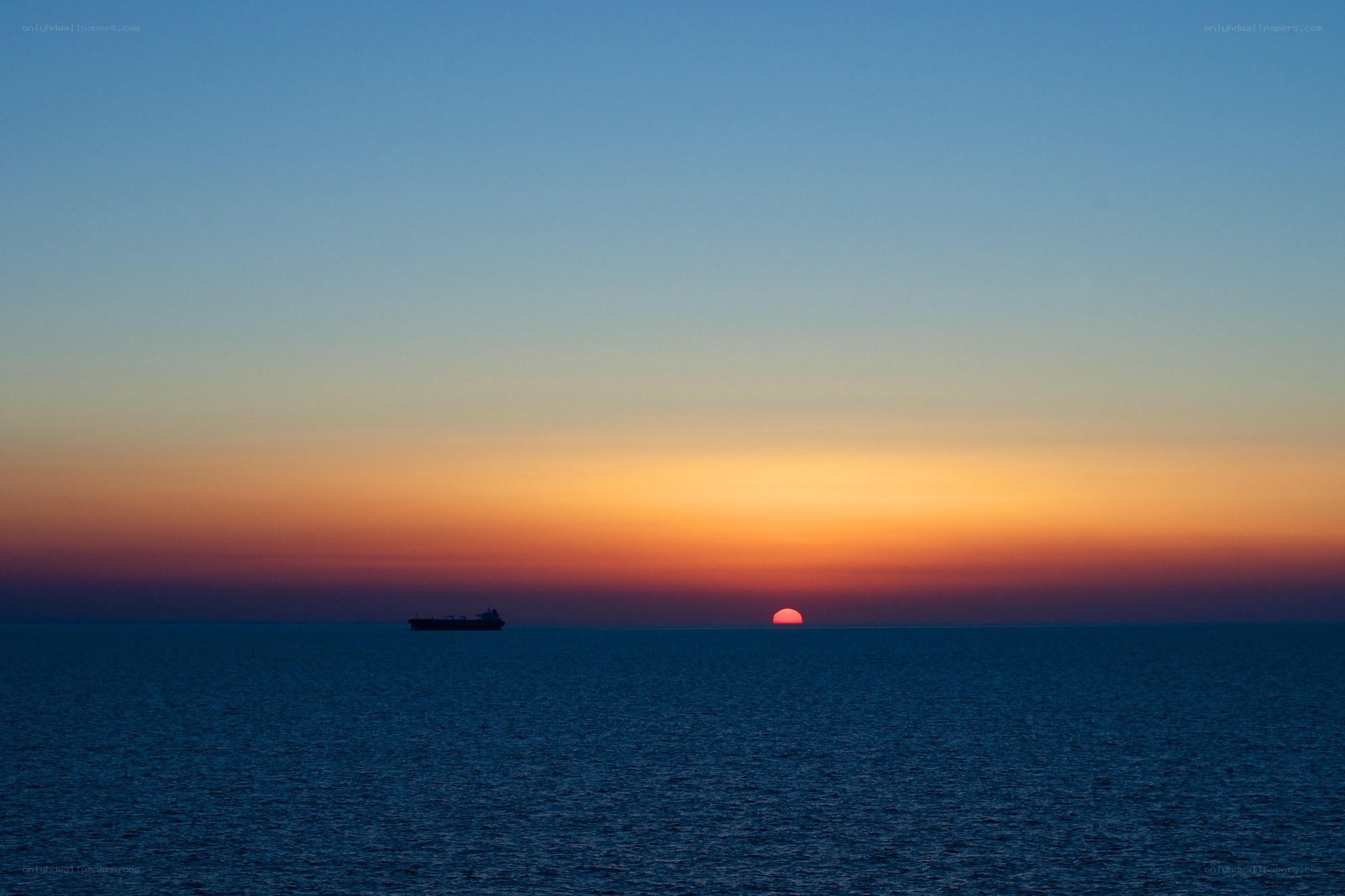 Sunset over the ocean with a ship