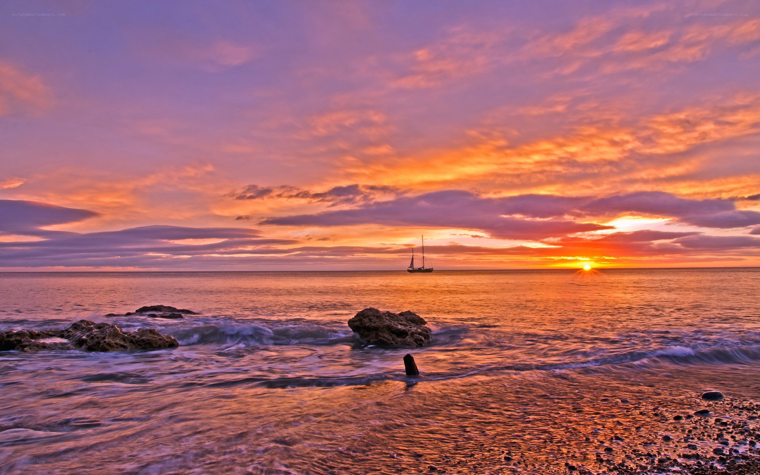 Sunset over the ocean with sailboat