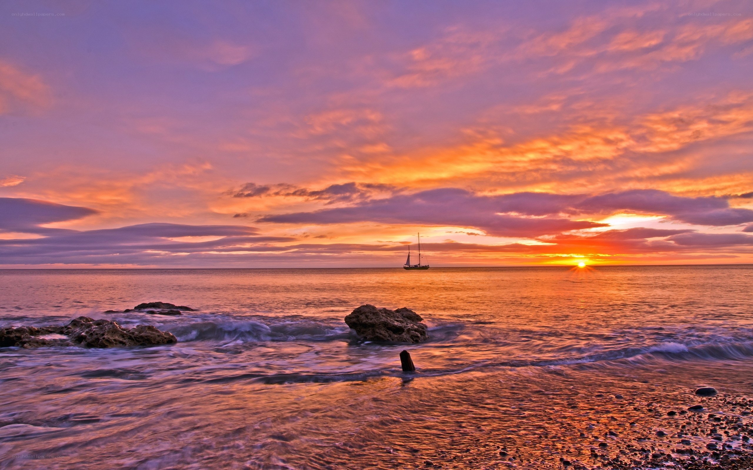 Sunset over the ocean with sailboat