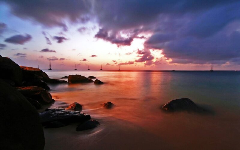 sunset over the ocean with sailboats