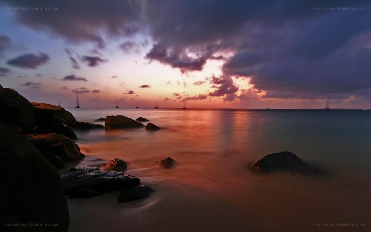 Sunset over the ocean with sailboats