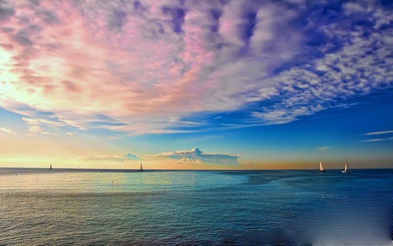 sunset over the sea with sailboats