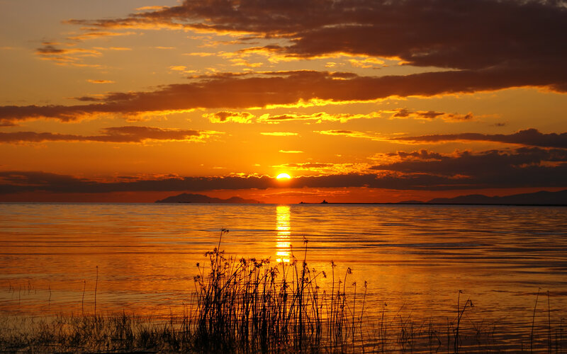 Sunset over Water — Orange, Serene, Photograph, Sun, Clouds, Mountains, Reeds, Yellow
