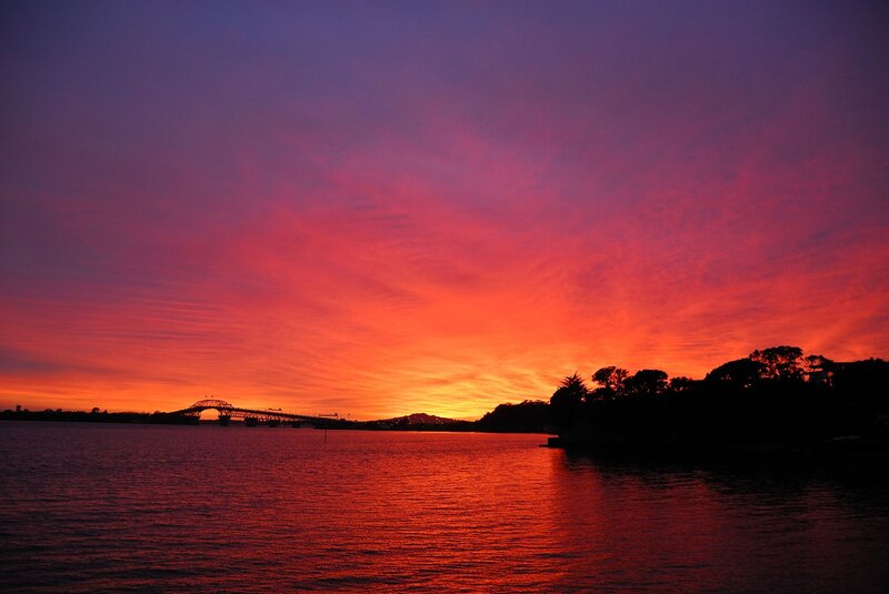 Sunset over Water — Red, Dramatic, Photograph, Bridge, Trees, Mountain