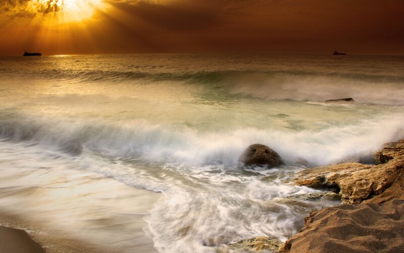 Sunset waves crashing on rocks