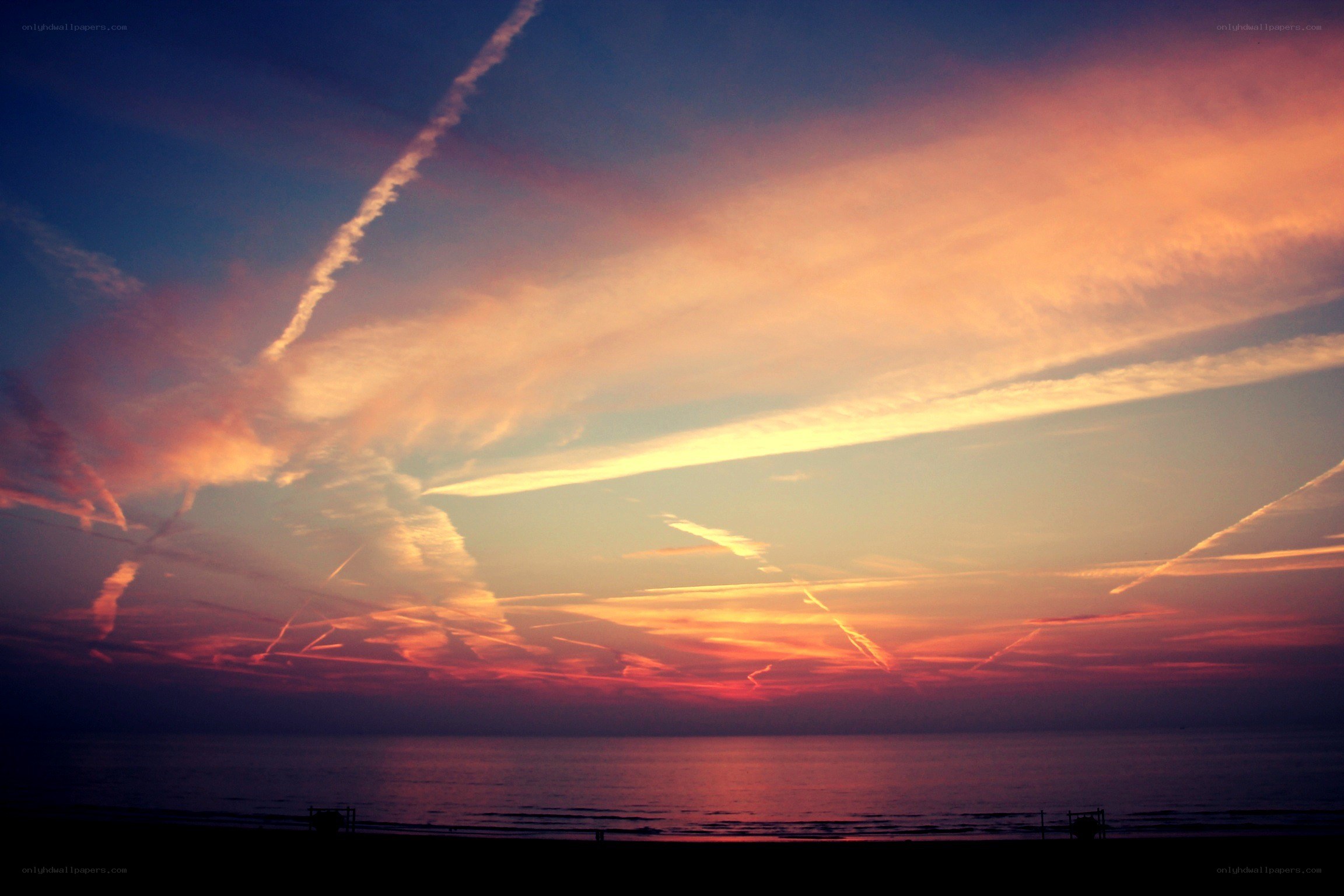 Sunset with contrails over the sea