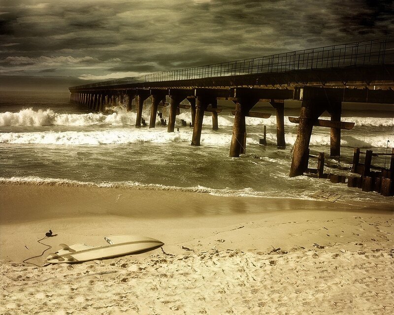 Surfboard on beach near pier