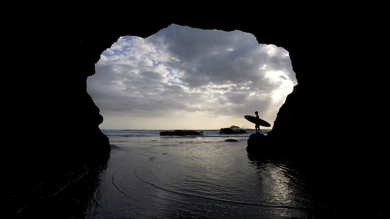 Surfer at cave entrance