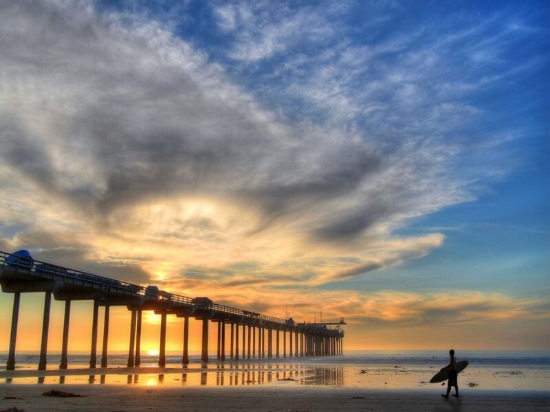 Surfer at sunset by the pier