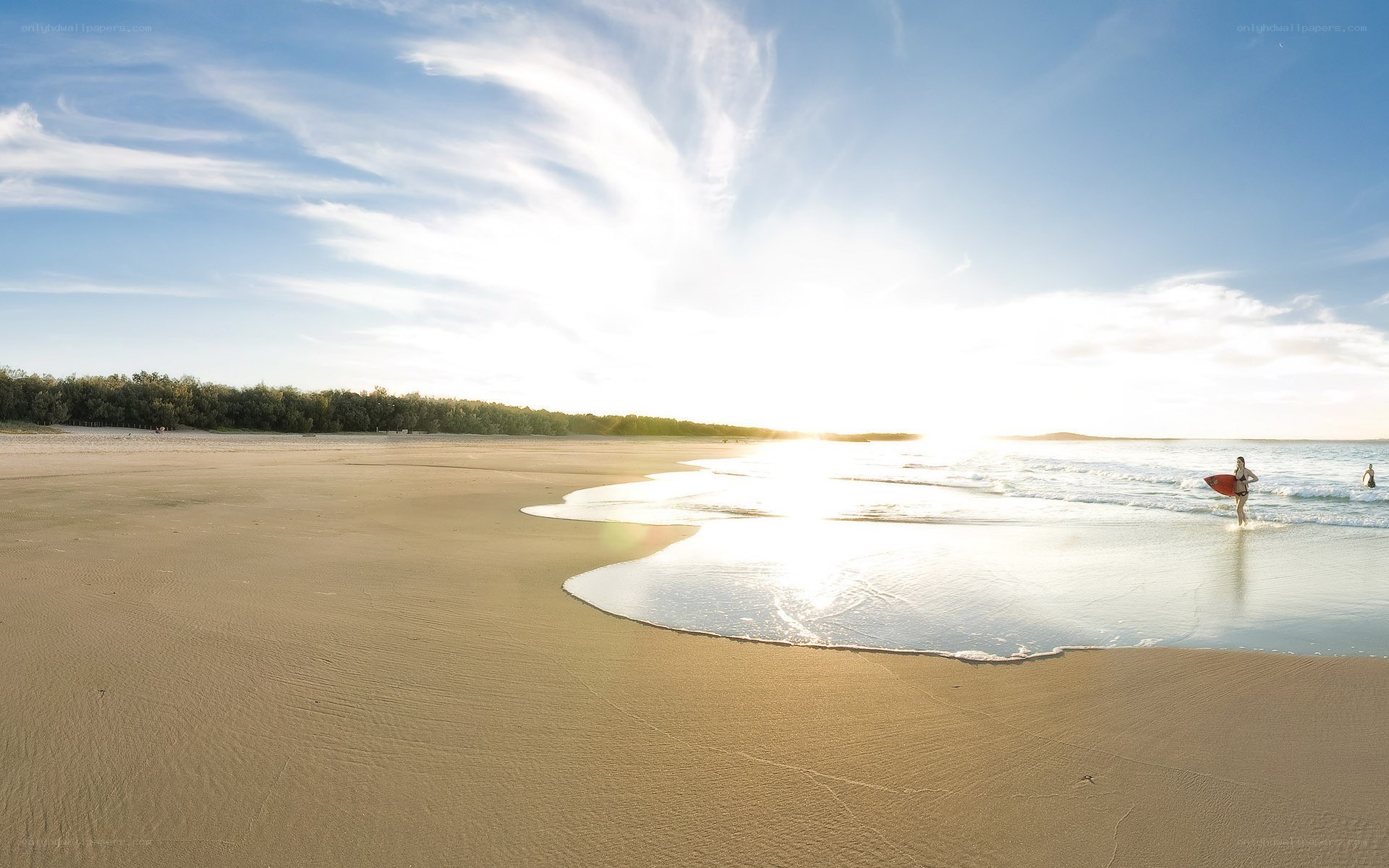 Surfer at sunset on a sandy beach