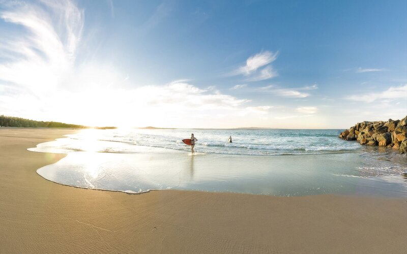 Surfer at sunset on a sandy beach