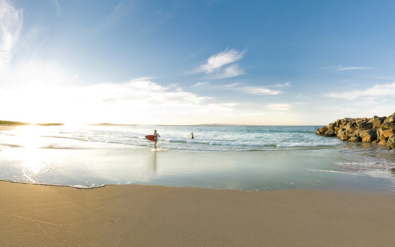 Surfer at sunset on a sandy beach