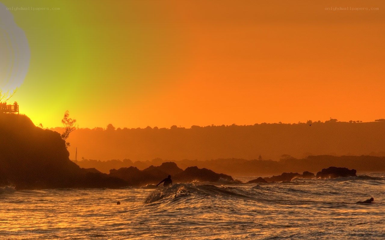 Surfer at sunset on rocky coast
