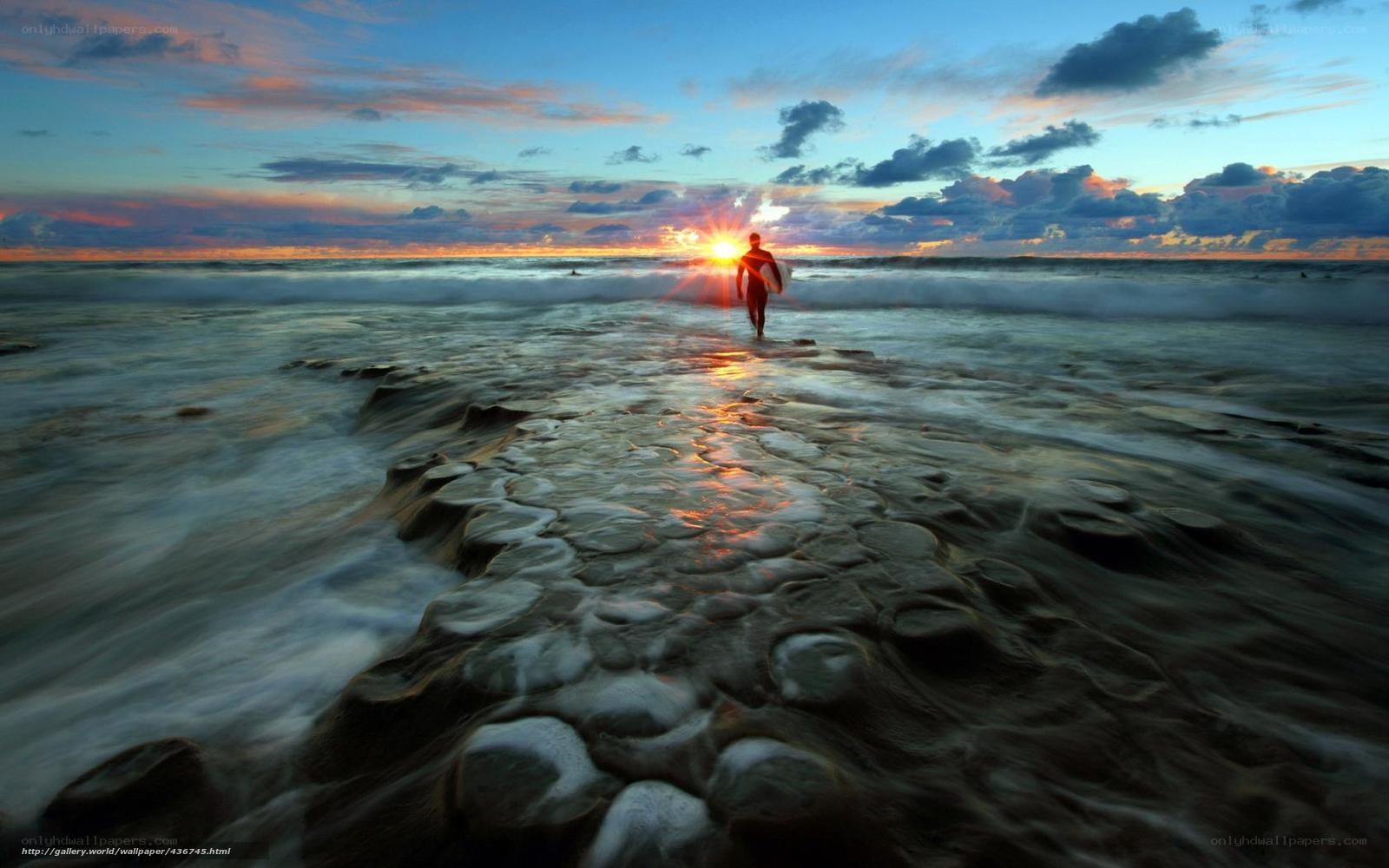surfer at sunset on rocky shore