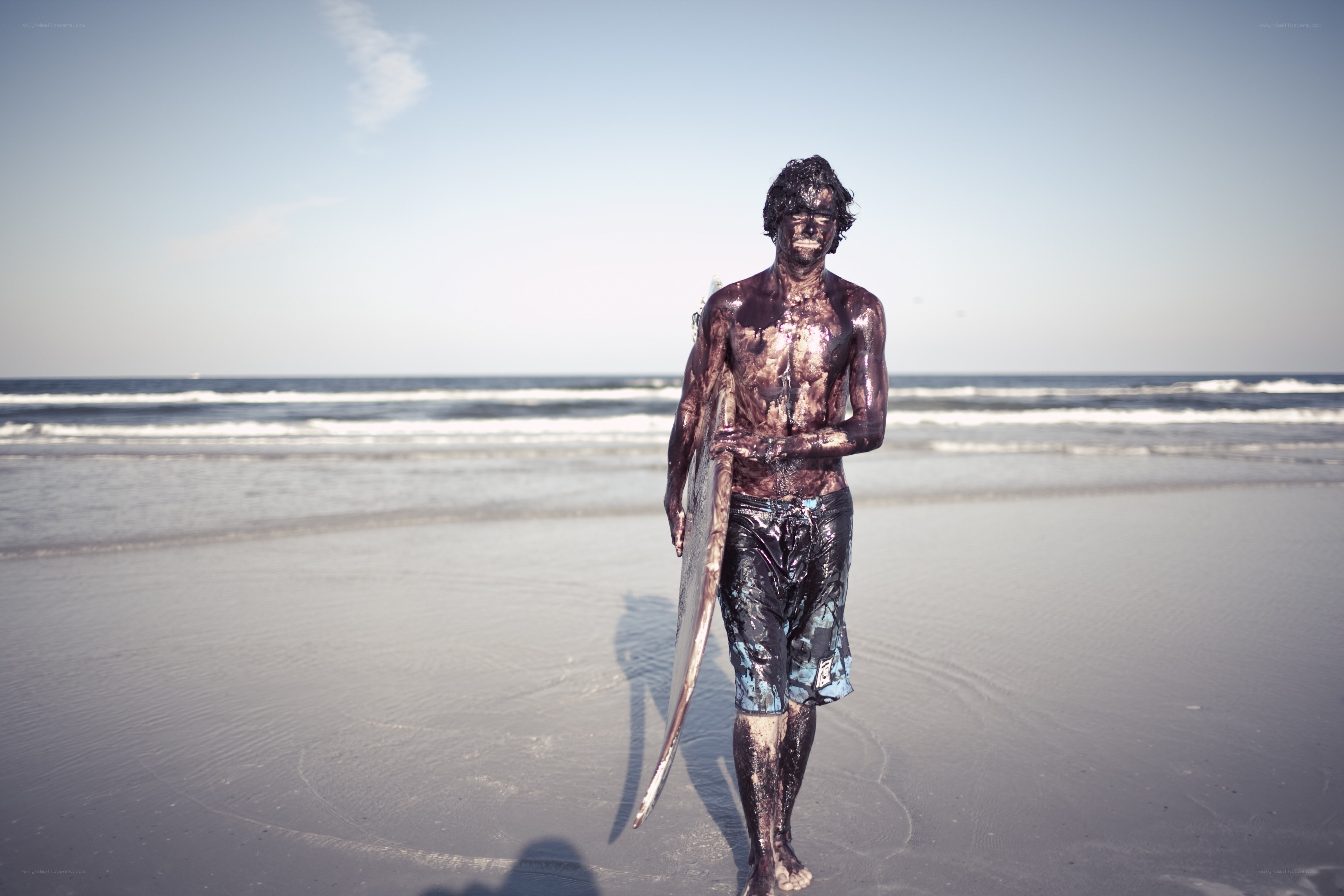 surfer covered in mud on beach