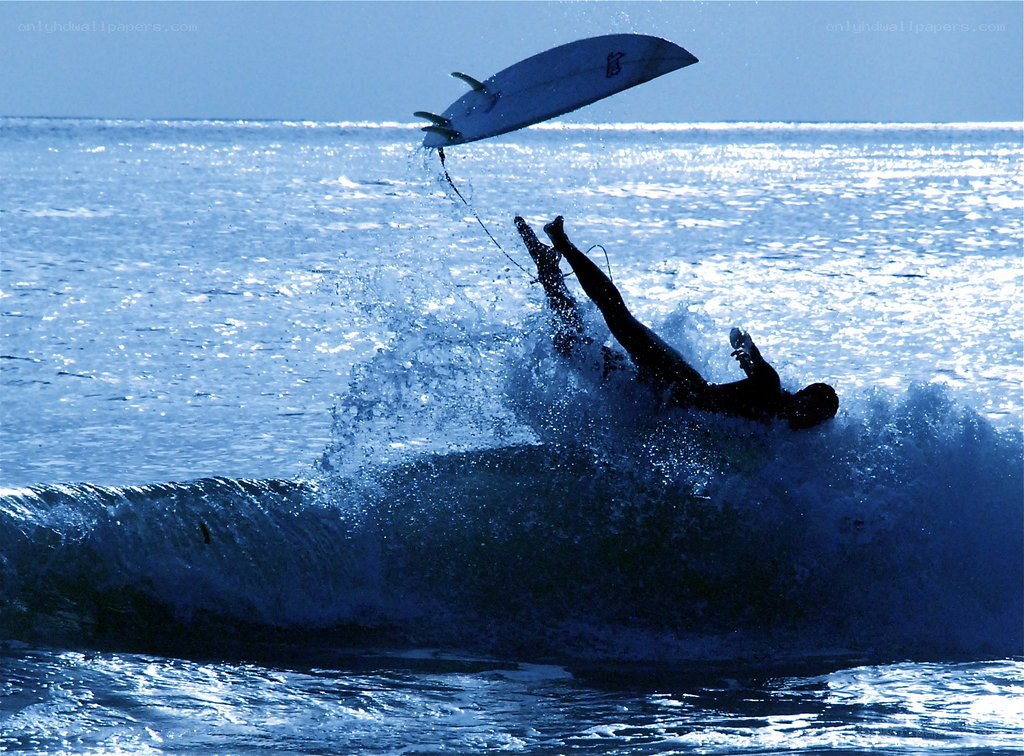 Surfer falls from wave