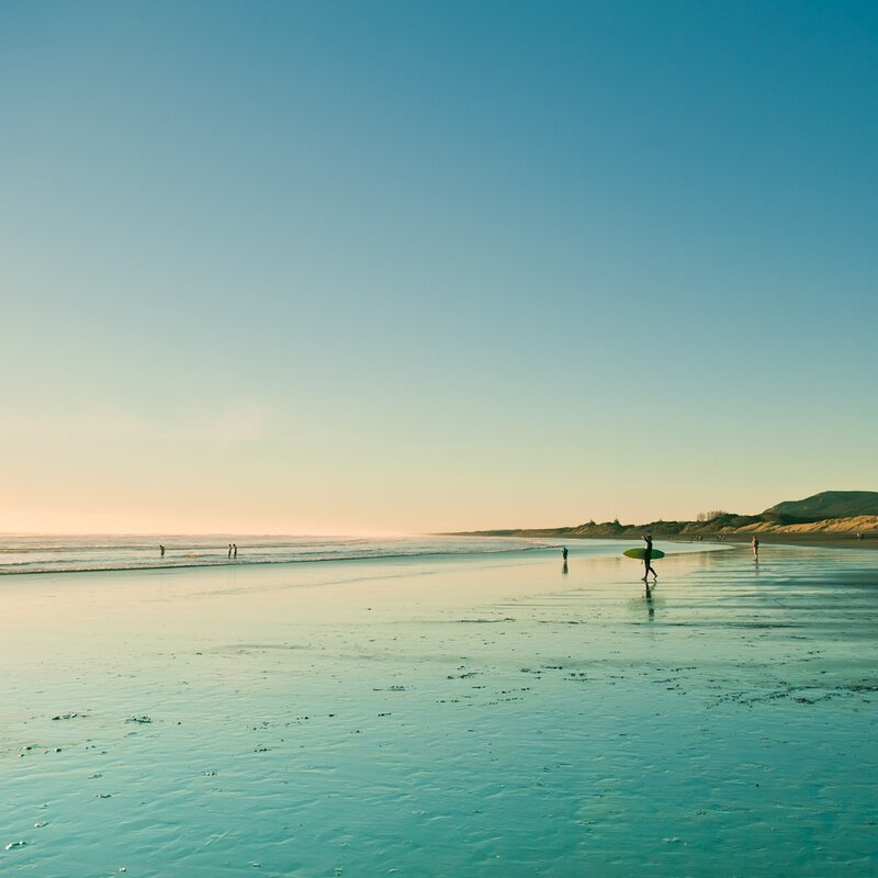 Surfer on a quiet beach at sunset