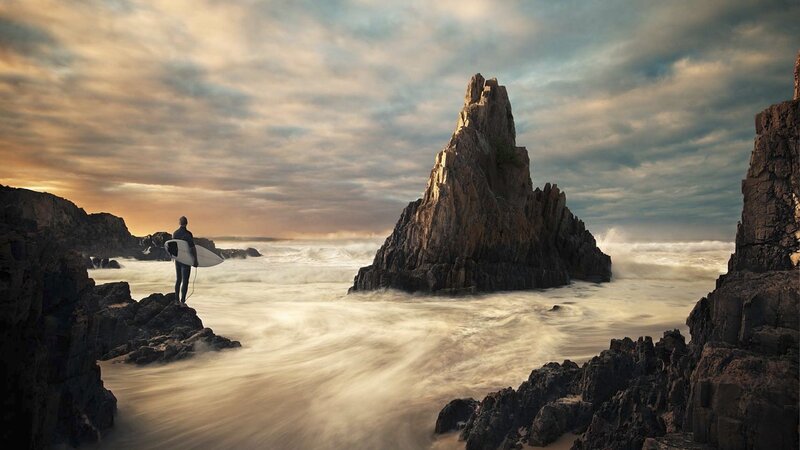 Surfer on Rocky Shore