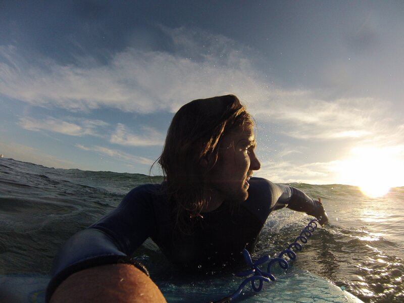 Surfer paddling at sunset