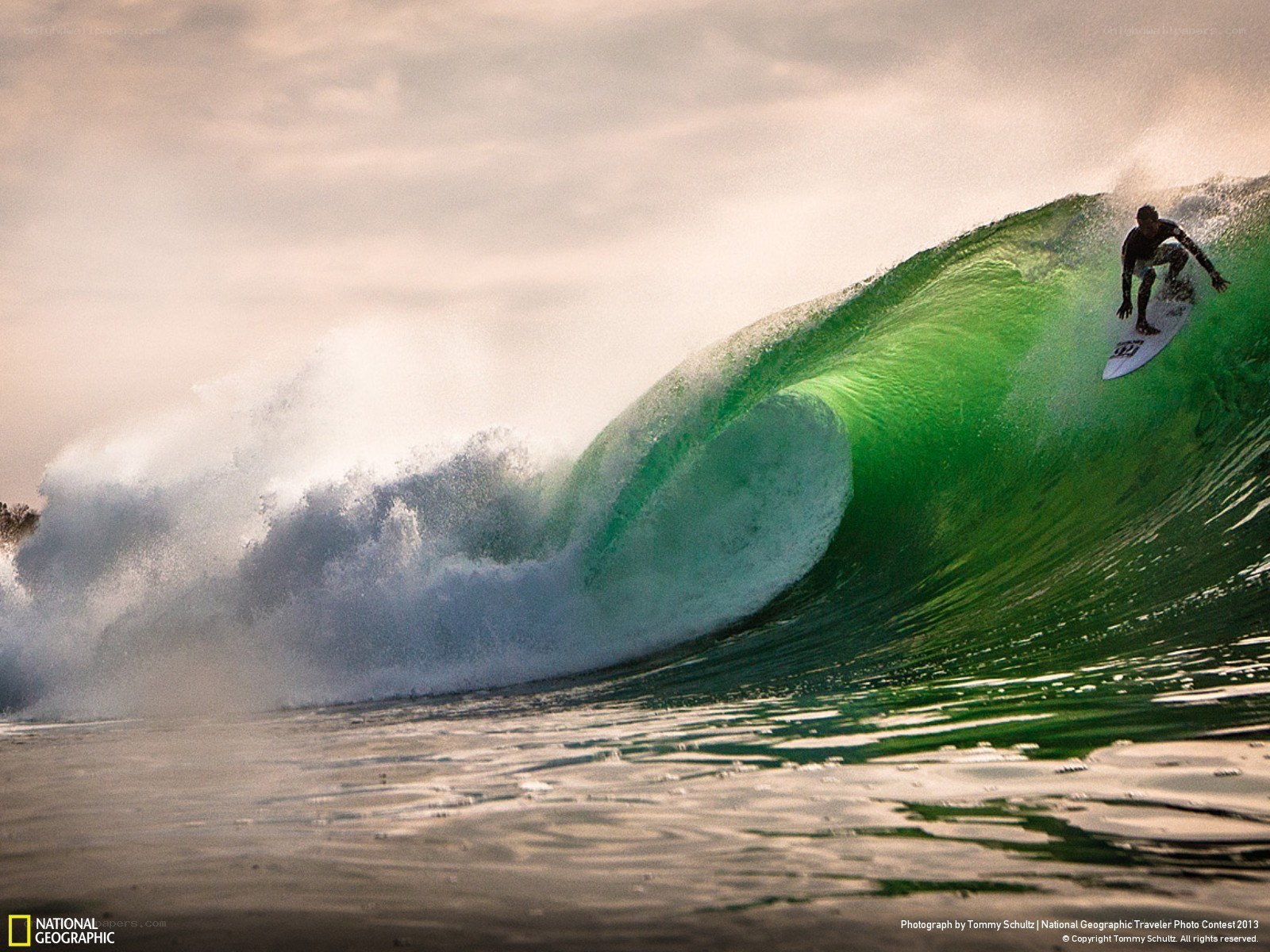 Surfer riding a green wave