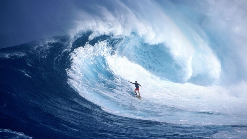 Surfer riding large ocean wave