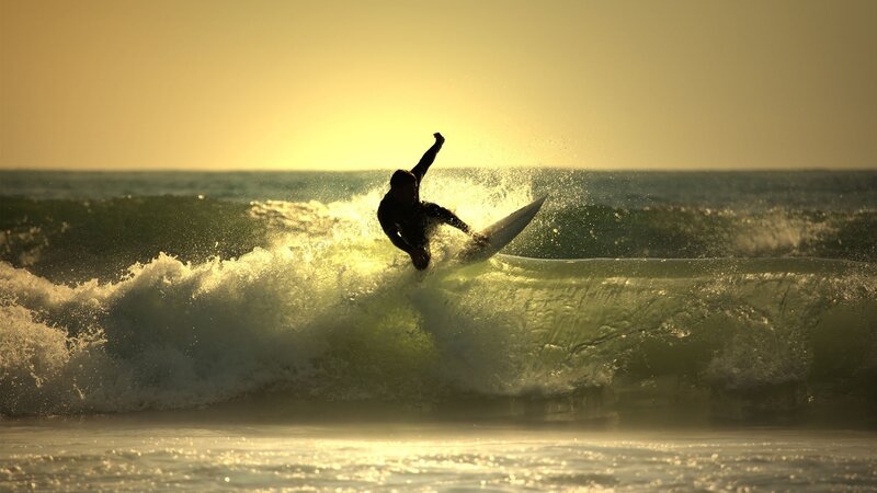 surfer riding wave at sunset