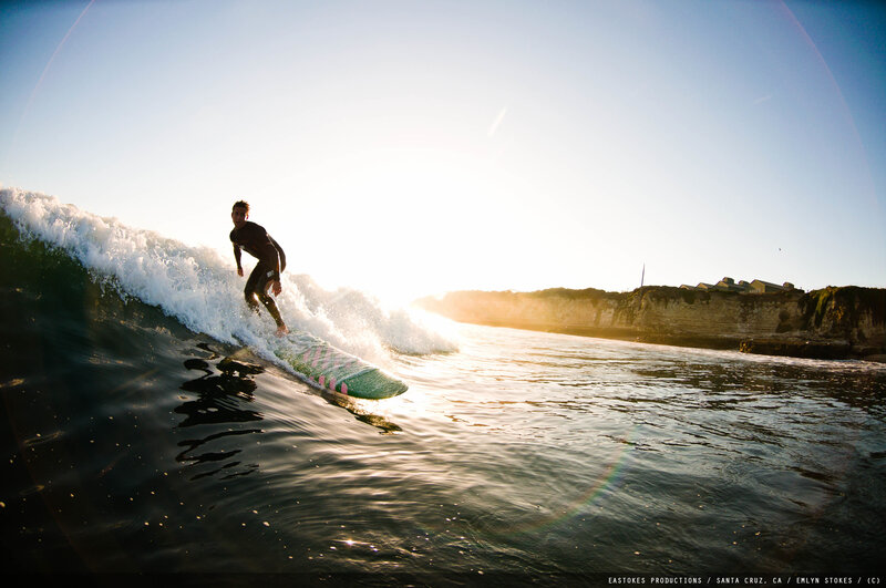 Surfer riding wave at sunset