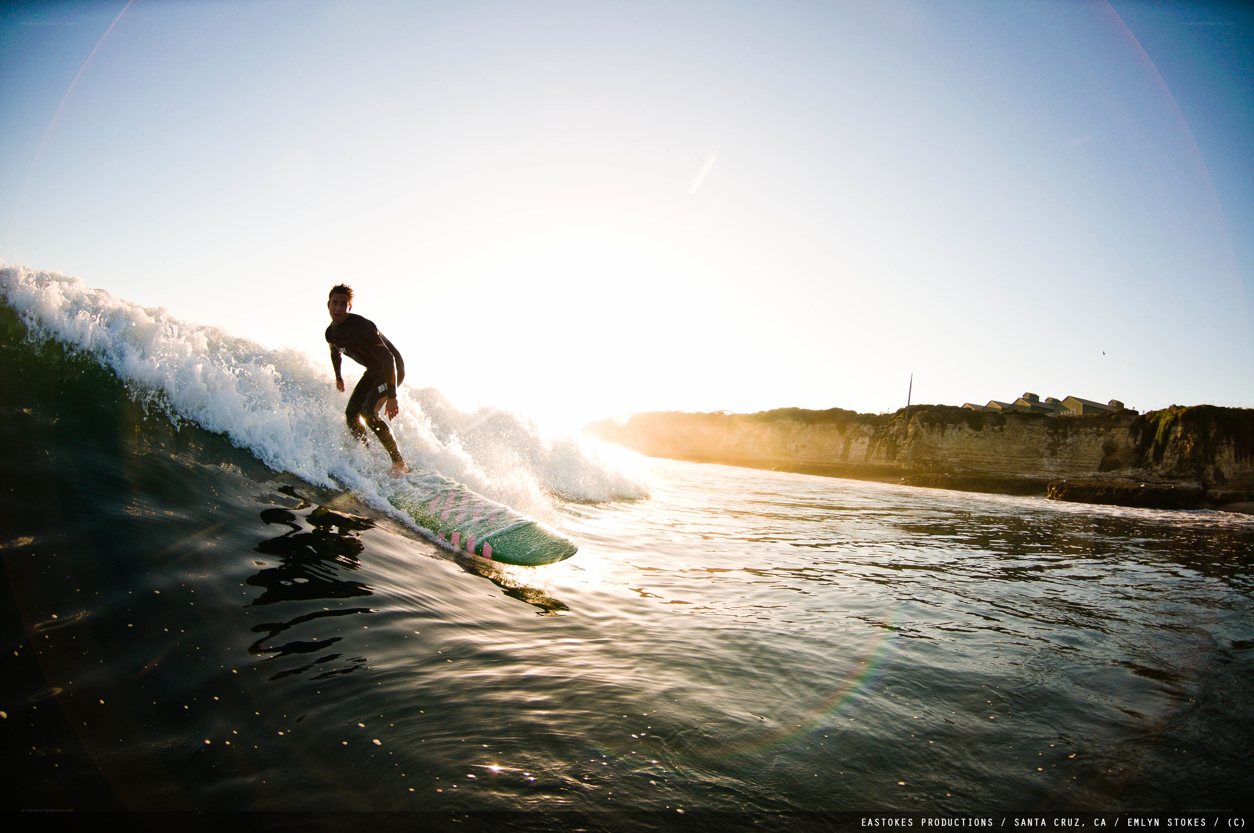 Surfer riding wave at sunset