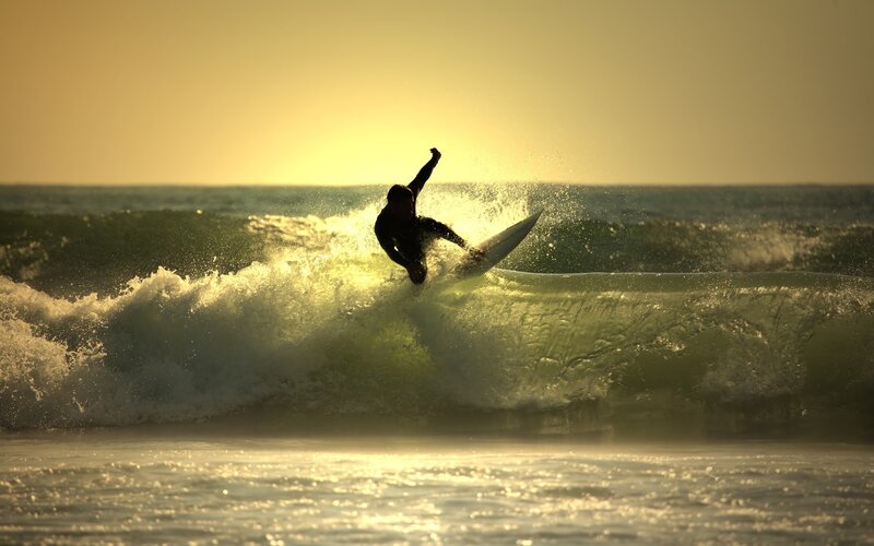 surfer riding wave at sunset