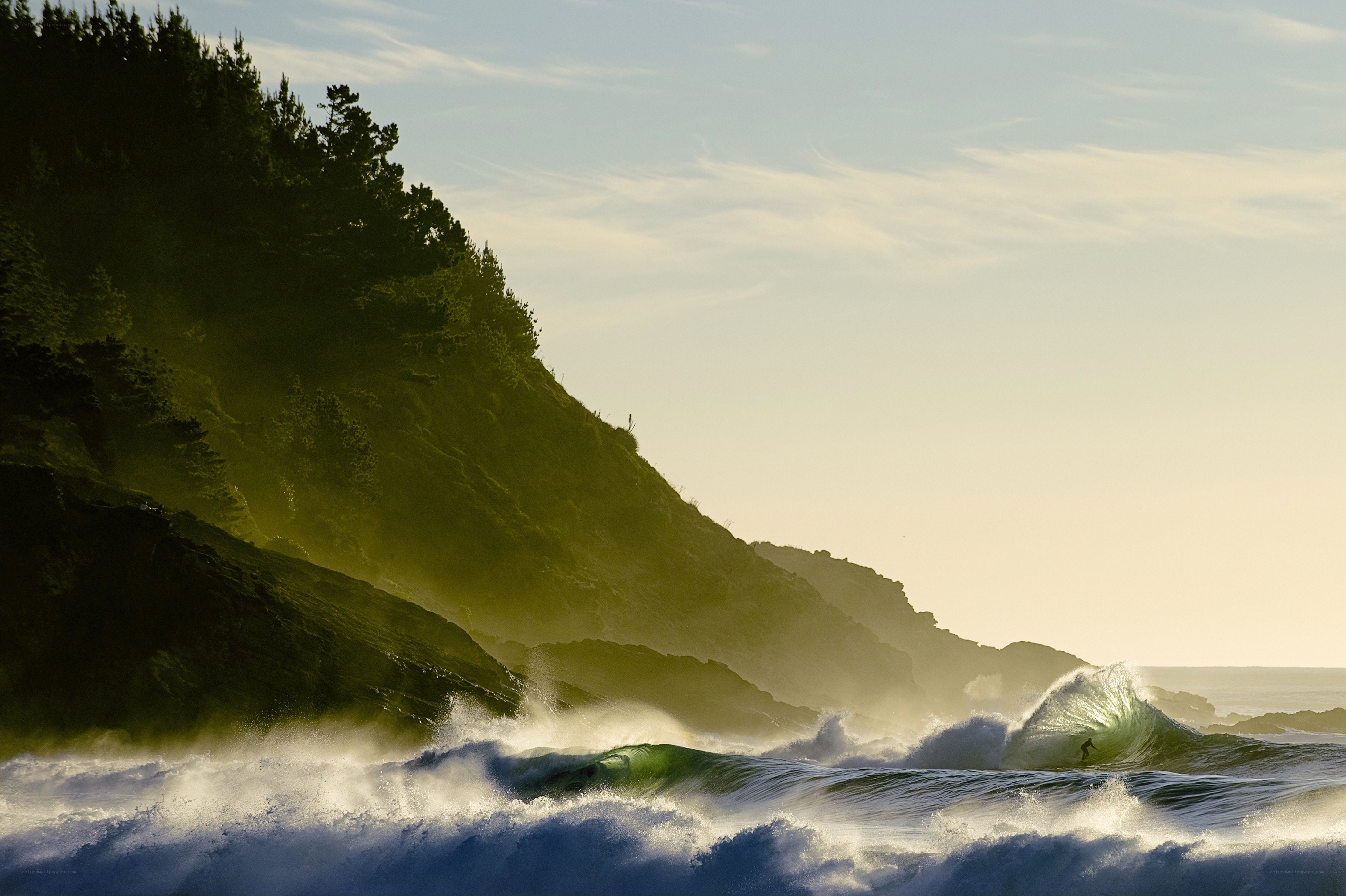 Surfer riding wave at sunset