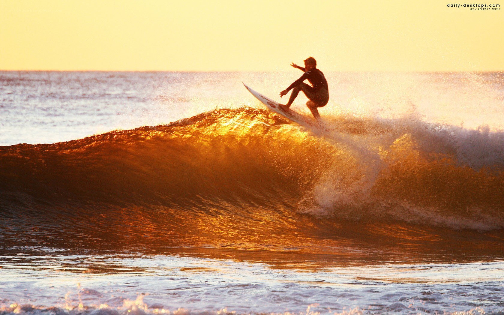 Surfer riding wave at sunset