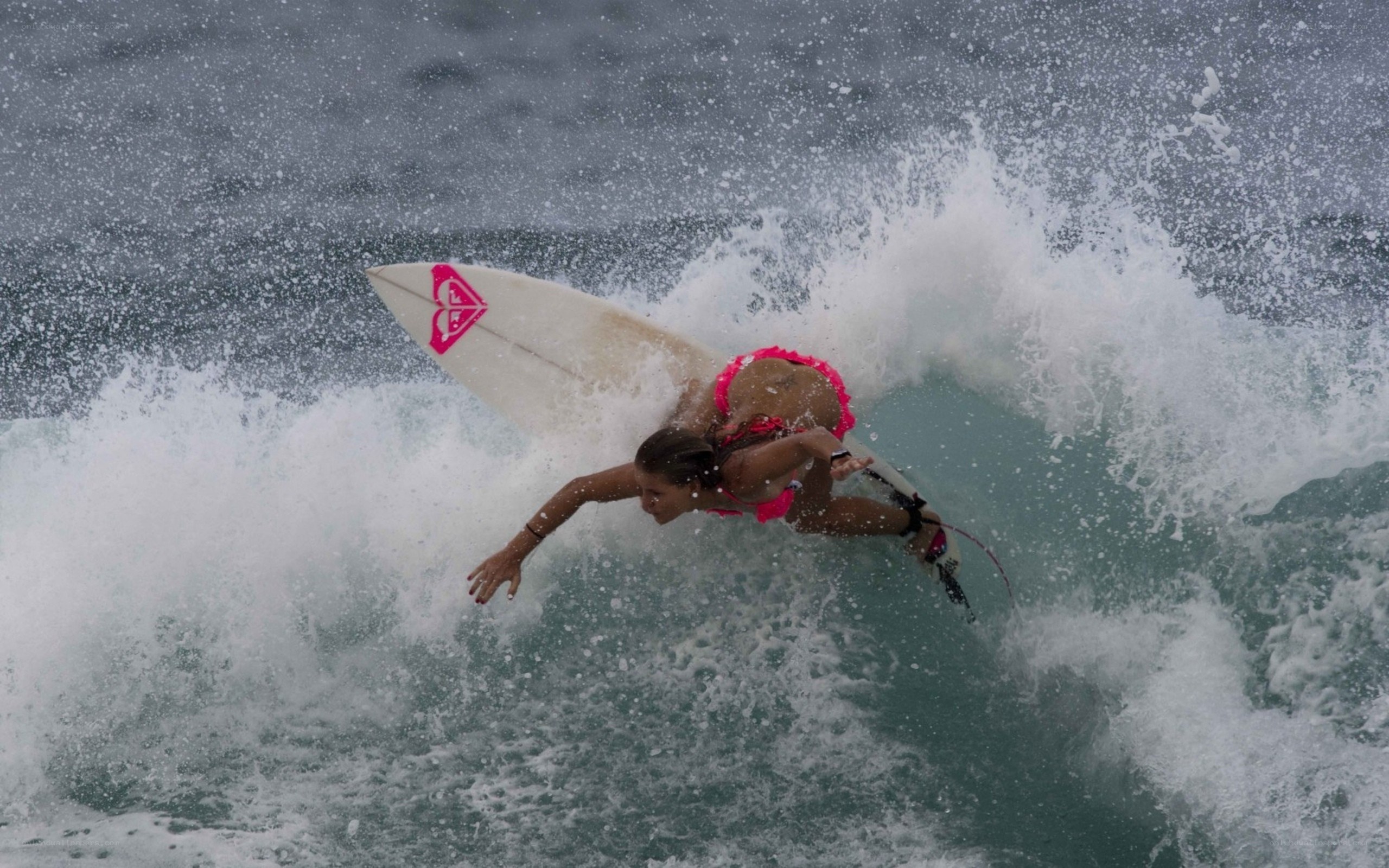 surfer riding wave in pink bikini
